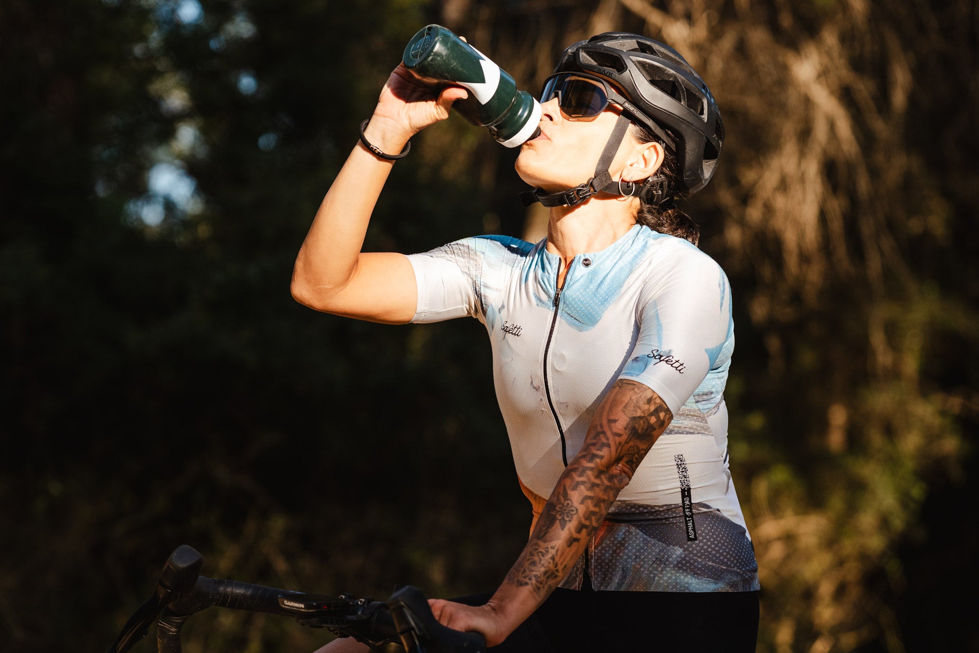 Radfahrerin trinkt aus einer MNSTRY-Trinkflasche.